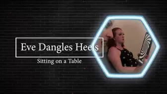Sitting on a table Dangling her high heels for you