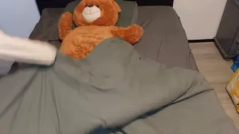 Sandra is trampling and crushing a huge teddybear on a bed