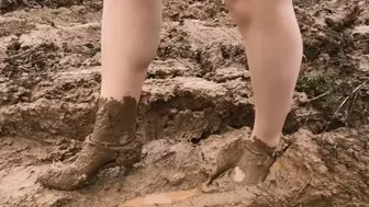 Girl in high heels and pantyhose is walking through deep soft mud
