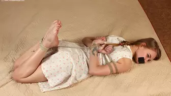Irene: tapegagged barefoot girl, wearing old-fashioned dress, hogtied with hemp rope, is wiggling on a mattress, trying to loosen her bonds (HD WMV)