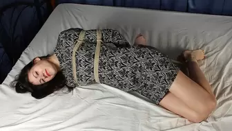 Norma: hogtied with hemp rope barefoot girl, wearing a dress, with nails painted in red, is wiggling on the bed, then tickled by camera man (HD MOV)