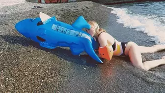 Alla inflates a blue inflatable shark with her mouth on the beach!!!