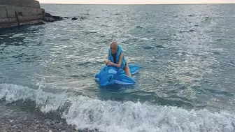 Alla rides a blue transparent whale in the sea and wears a blue inflatable vest
