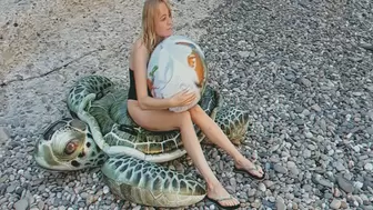 Alla blows off a beach ball while sitting on an inflatable turtle on the beach!!!